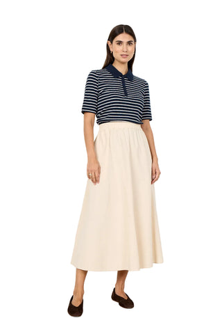 Woman wearing a striped shirt and beige skirt against a white background