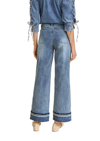 Person wearing blue denim wide-leg pants on a beige background