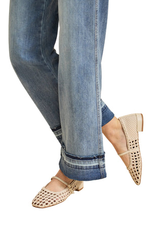 Person wearing blue jeans and beige flats on a beige background