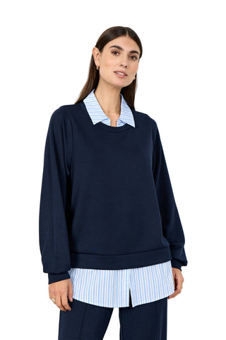 Woman wearing navy top with white and navy striped collar and hemline on   a white background