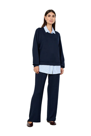 Woman wearing a navy top with a blue and white collar and hemline on a white background