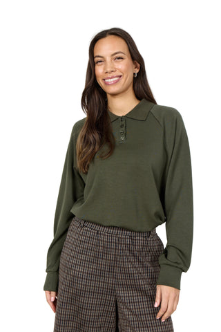 Woman wearing an olive green blouse and plaid pants on a white background