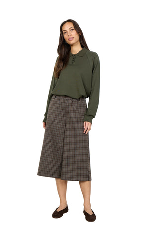 Woman wearing a green blouse and plaid skirt against a white background