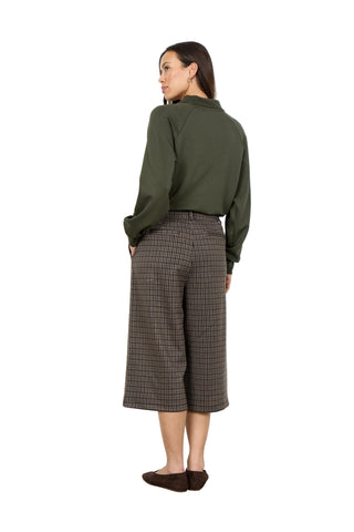 Woman wearing a green shirt and plaid pants against a white background