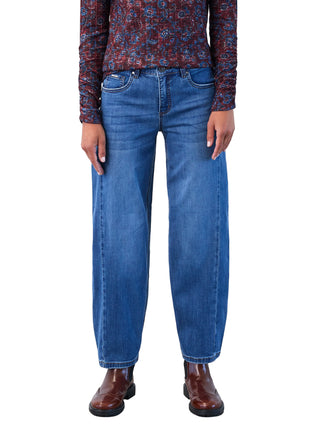 Person wearing blue jeans and a patterned top against a white background