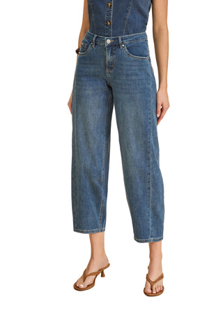 Person wearing a blue denim jumpsuit on a beige background