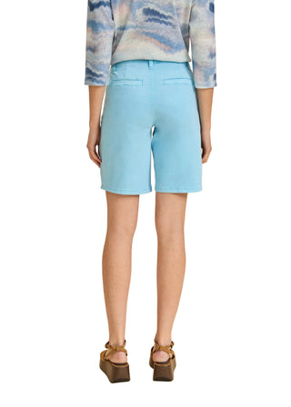 Person wearing light blue shorts on a beige background