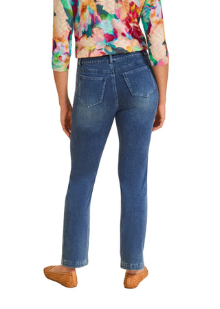 Person wearing blue jeans and a colorful top on a beige background