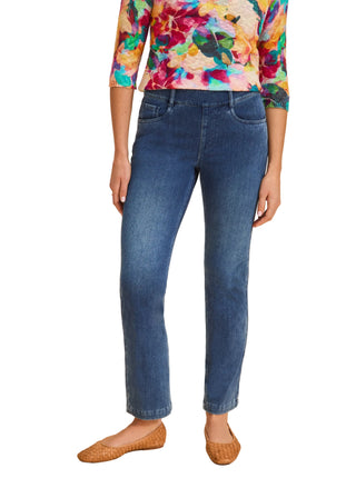 Person wearing blue jeans and a colorful floral top on a beige background