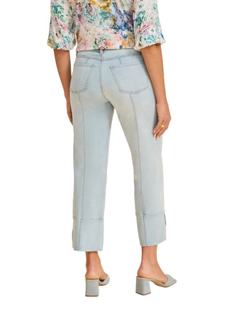 Person wearing light blue jeans and a floral top on a beige background