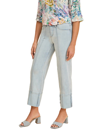 Person wearing light blue jeans and a floral top on a beige background