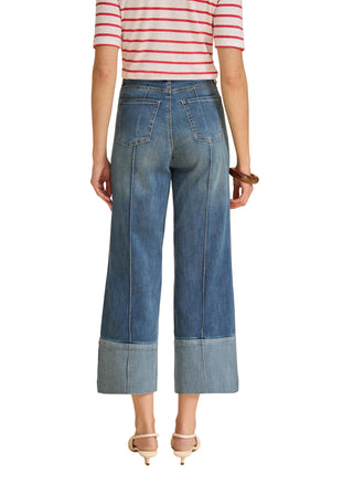 Person wearing a striped shirt and blue jeans on a beige background