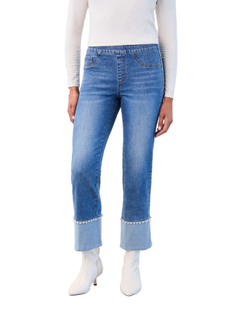 Person wearing blue jeans with white booties on a plain background