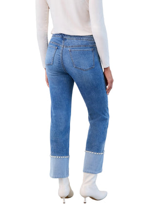Person wearing blue jeans and white shoes against a plain background