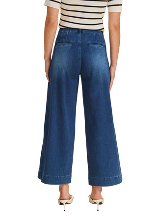 Person wearing blue wide-leg jeans and a striped shirt on a beige background