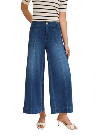 Person wearing blue wide-leg jeans and a striped shirt on a beige background