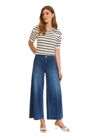 Woman wearing a striped shirt and wide-leg jeans on a beige background