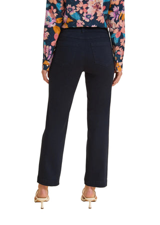 Person wearing navy pants with a floral top on a beige background