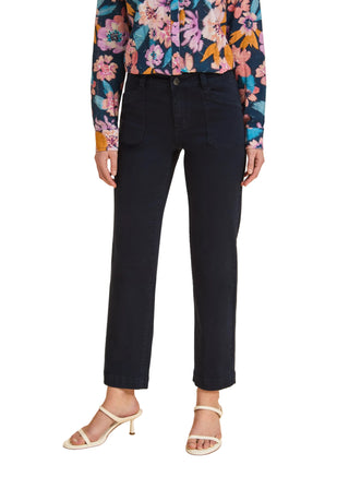 Person wearing black jeans with a colorful floral shirt on a beige background