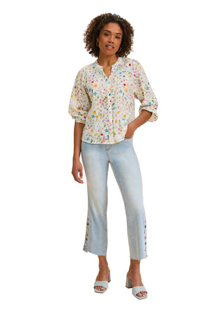 Woman wearing a floral blouse and light blue jeans on a beige background