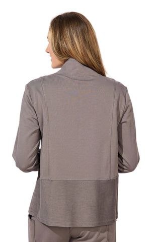 Woman wearing a gray jacket and pants against a white background