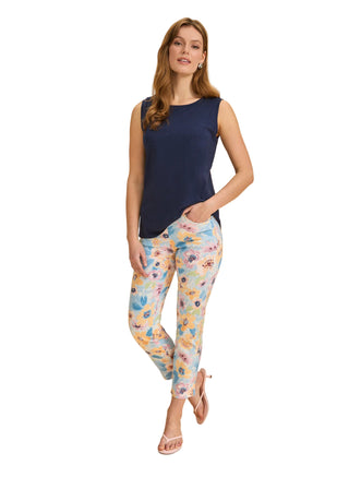 Woman wearing a navy sleeveless top and floral pants on a beige background