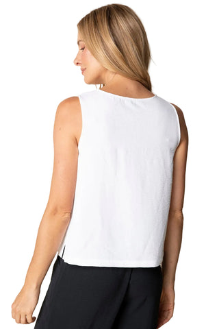 Woman wearing a white sleeveless top against a beige background