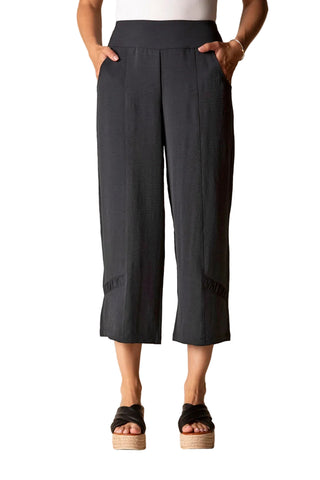 Person wearing black wide-leg pants on a beige background