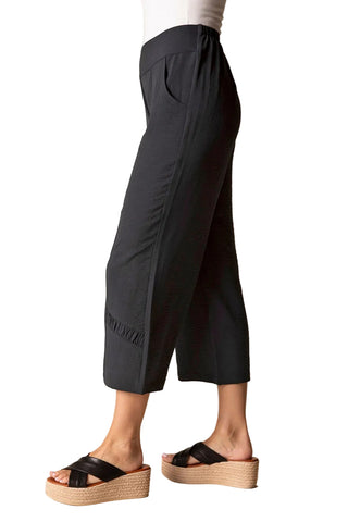 Black pants worn by a person on a beige background