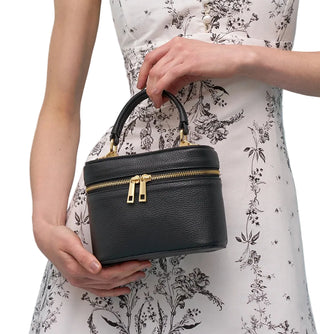 Woman holding a black handbag against a light blue background