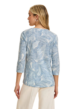 Woman wearing a blue patterned top against a beige background