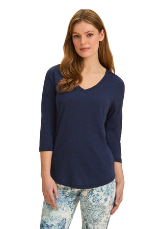 Woman wearing a navy blue top and floral pants on a beige background