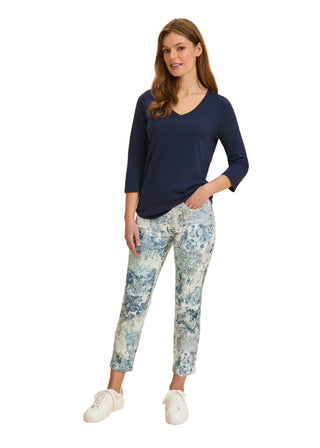 Woman wearing a navy top and floral pants on a beige background