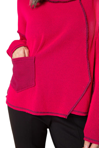 Close-up of a bright pink textured sweater with a pocket on a beige background