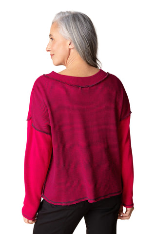 Woman wearing a red long-sleeve top against a beige background