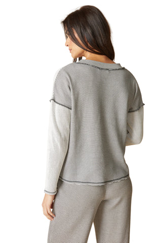 Woman wearing a gray striped outfit against a beige background