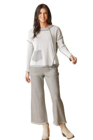 Woman wearing a light gray sweater and pants on a beige background