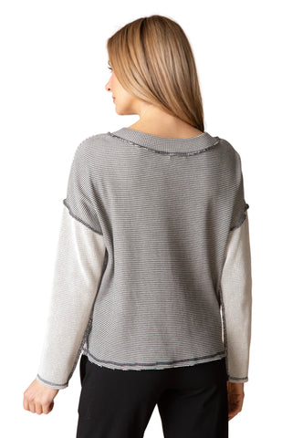 Woman wearing a gray and black striped sweater on a beige background