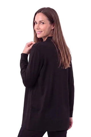 A woman with long brown hair is shown from the back wearing a black long-sleeve tunic top against a light gray studio background.