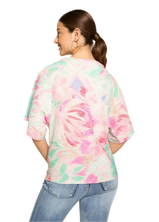 Woman wearing a colorful tie-dye shirt and jeans on a white background