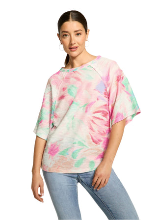 Woman wearing a colorful tie-dye shirt and jeans on a plain background