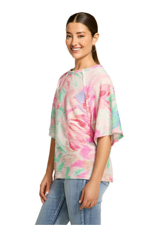 Woman wearing a colorful tie-dye shirt and jeans on a plain background