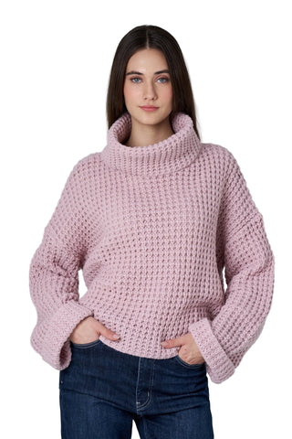 Woman wearing a pink knitted sweater against a plain background