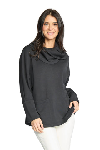 A woman modeling a black long-sleeve cowl neck top with front pockets, paired with white pants, against a light gray studio background.