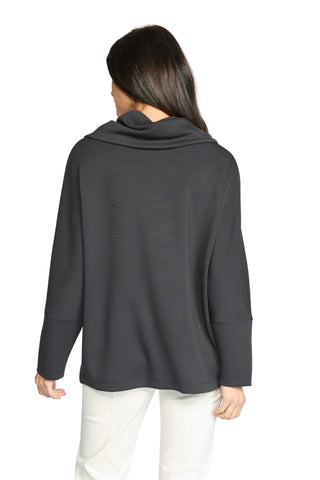 A woman shown from the back wearing a dark charcoal gray cowl-neck long-sleeve top and white pants, photographed against a light gray studio background.
