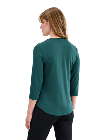 Woman wearing a green top with black pants on a white background