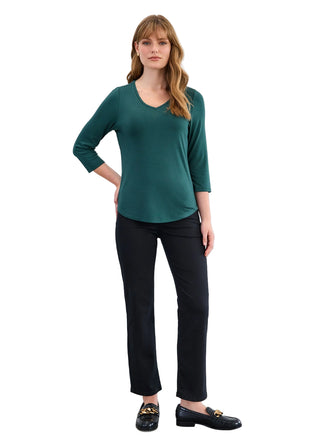 Woman wearing a green top and black pants against a white background