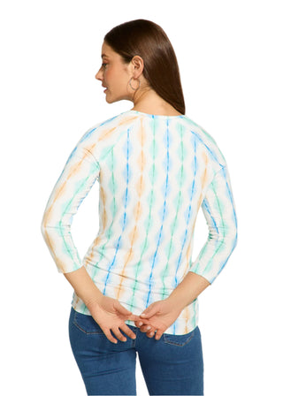 Woman wearing a colorful tie-dye shirt and blue jeans on a white background