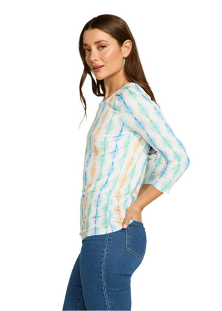 Woman wearing a colorful tie-dye shirt and blue jeans on a white background