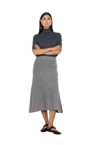 Woman wearing a gray turtleneck and skirt against a white background